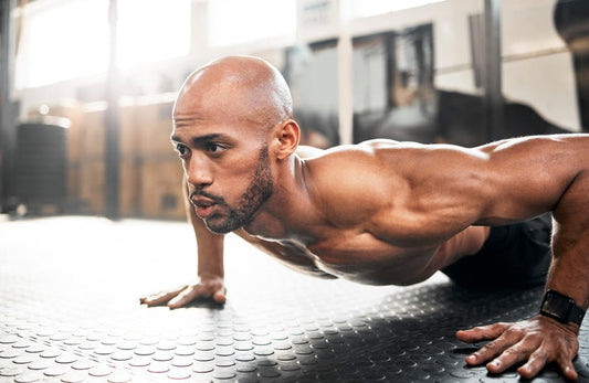 bald man doing a pushup on the floor of a gym