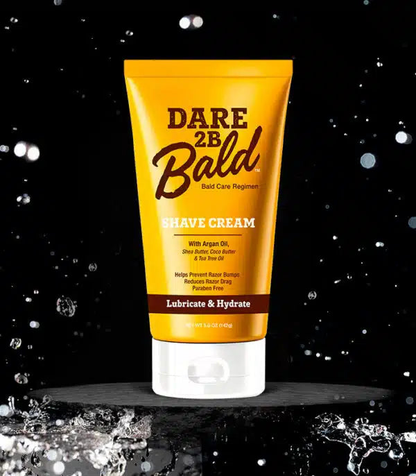 Dare 2B Bald shave cream tube on a black background with water droplets.